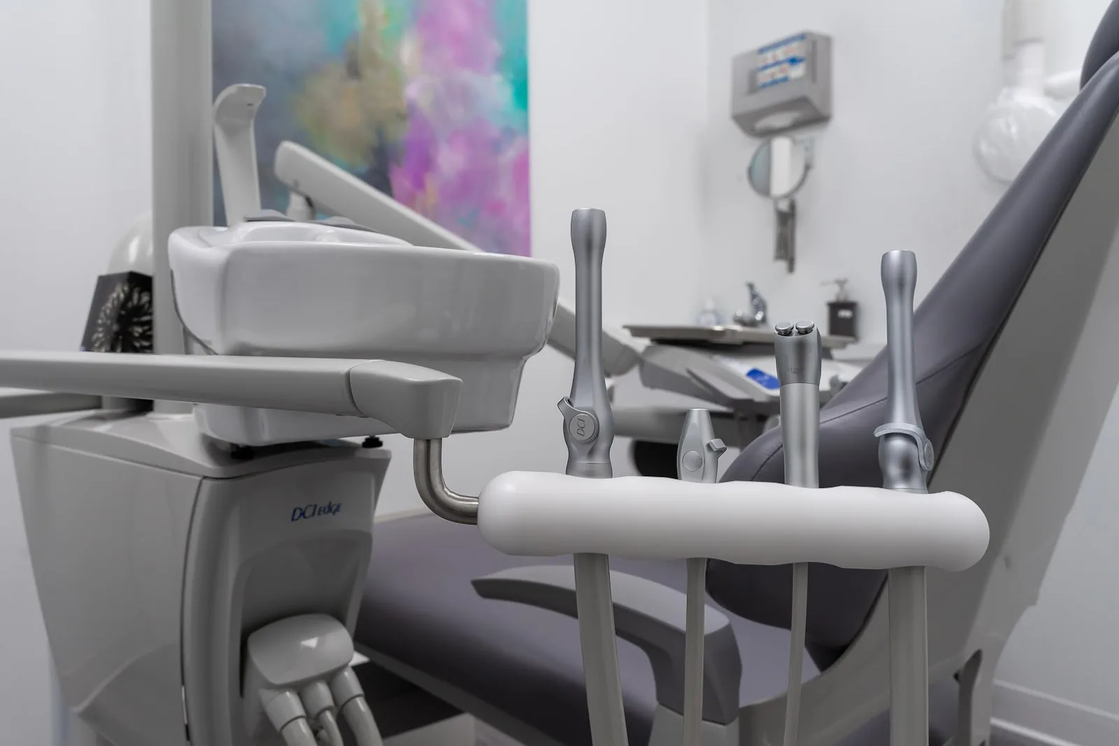 A treatment room at the clinic: the dental chair beside its instrument tray and delivery unit