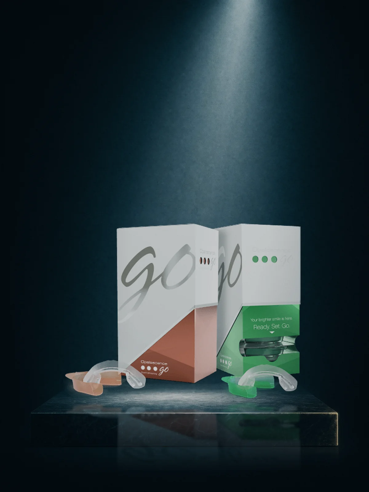 Two Opalescence Go cartons with their prefilled trays set out in front of them, lit on a dark plinth